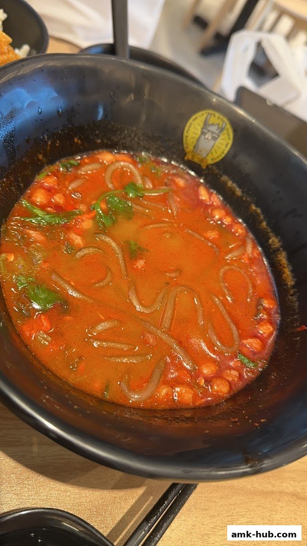 A close-up of a steaming bowl of Mala Tang with noodles and vegetables in a spicy broth.