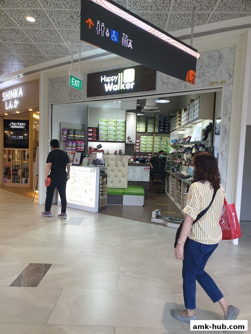 The entrance of Happy Walker shoe store with shoes displayed inside and customers walking by.