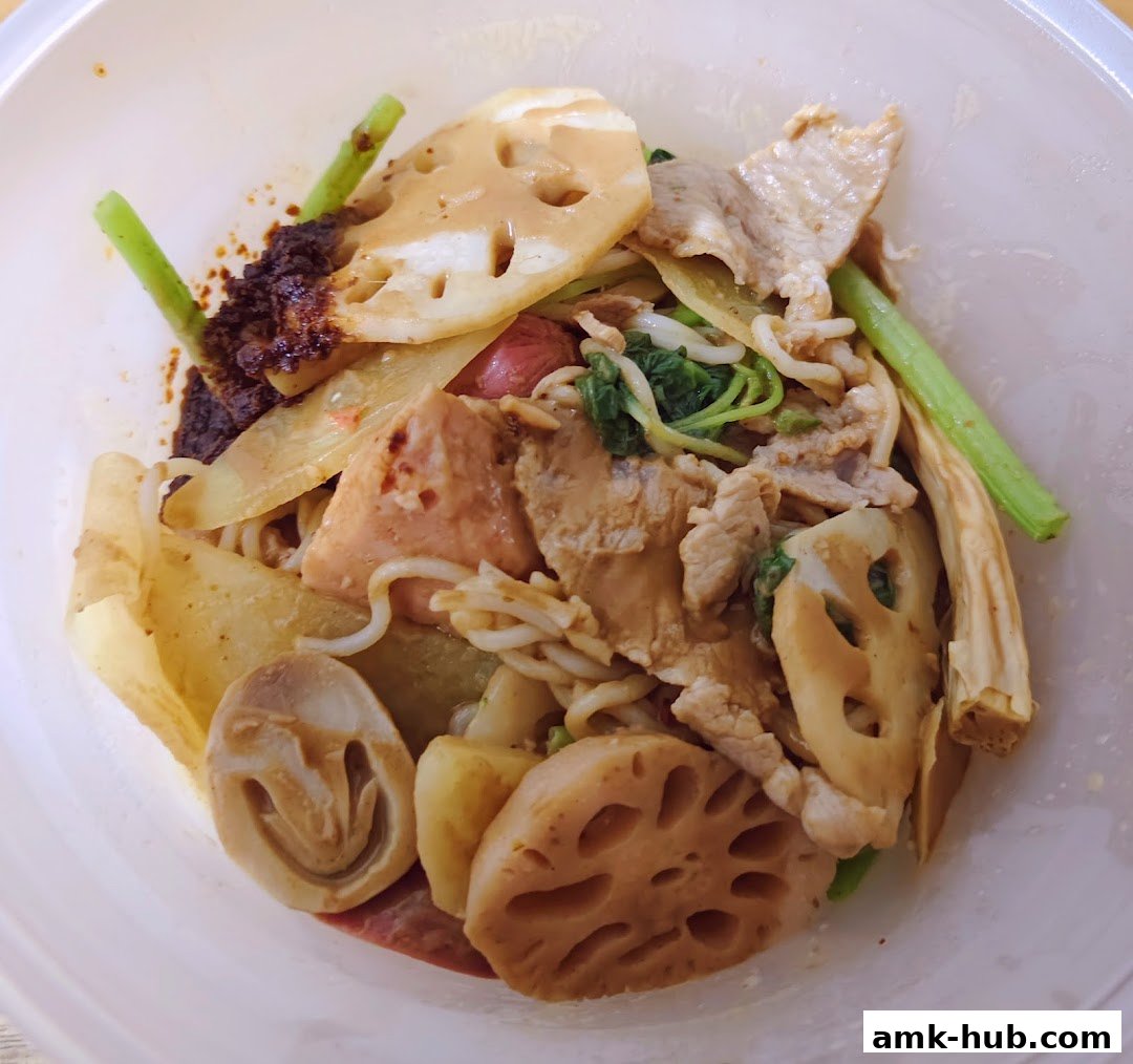 A close-up of a bowl of Mala Tang with various ingredients including lotus root, meat, and vegetables.