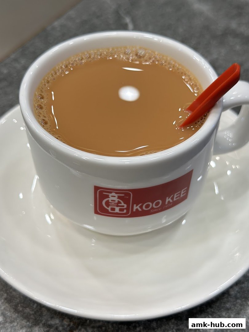 A close-up shot of a steaming cup of milk tea with a red spoon.
