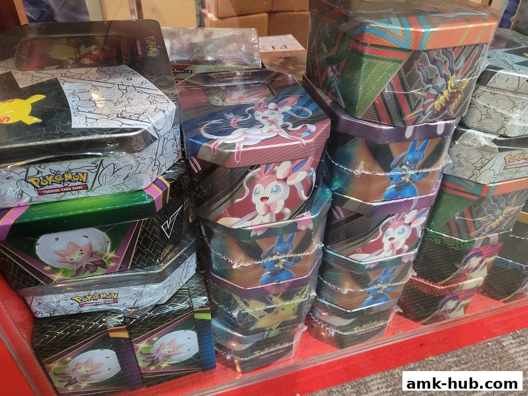 A display of stacked Pokemon trading card tins featuring various characters and designs.