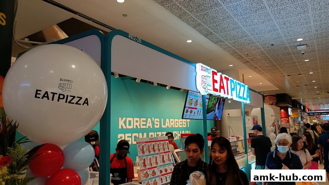 Eat Pizza shop front with a large balloon and a menu displayed.