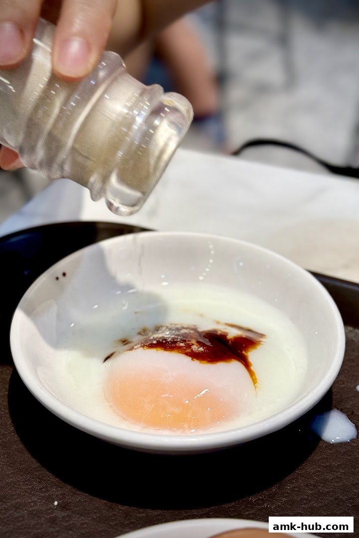 A person seasons a soft-boiled egg with soy sauce and pepper.