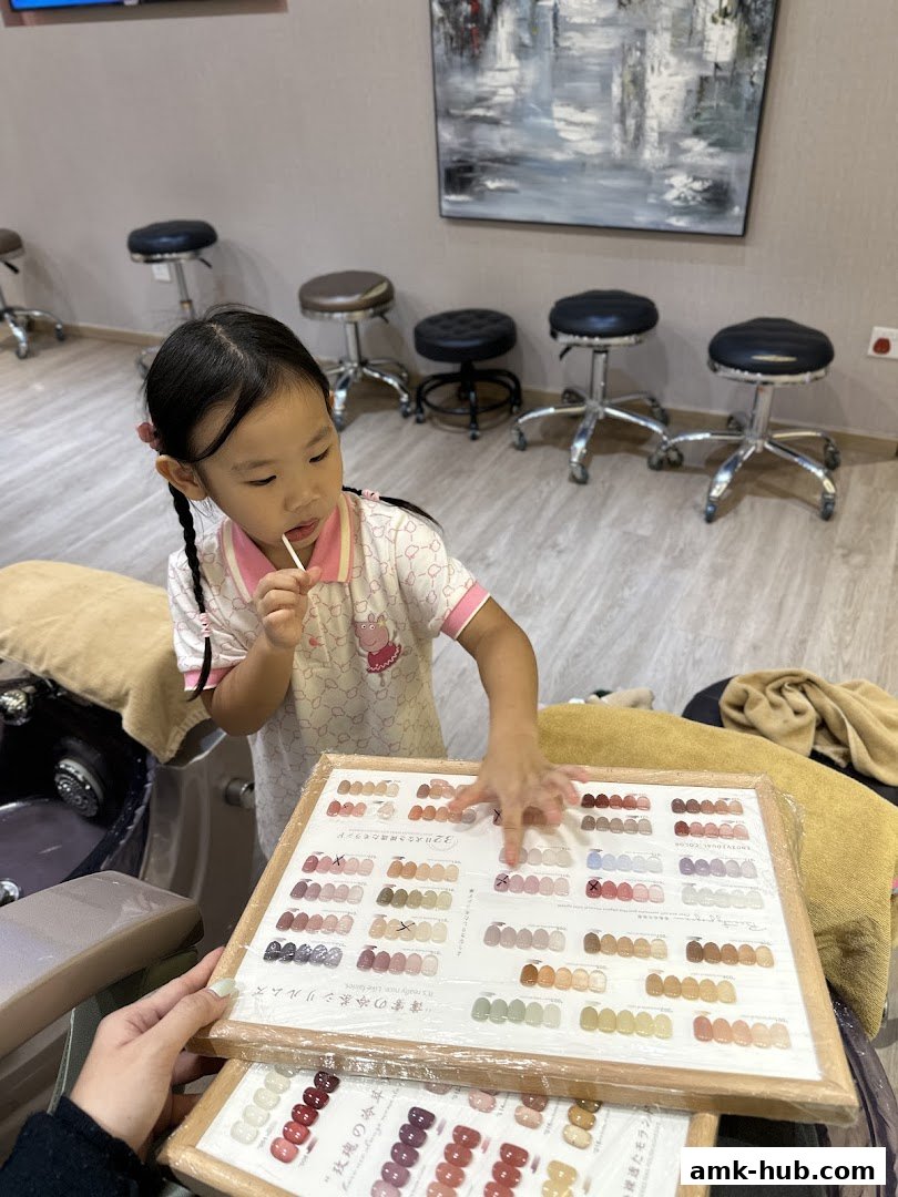 A young girl looks at a nail color swatch book at a nail salon.