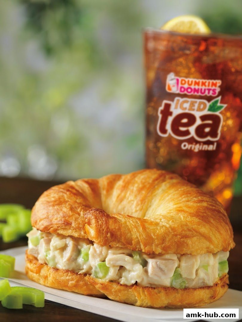 A delicious chicken salad croissant sandwich with a glass of iced tea.