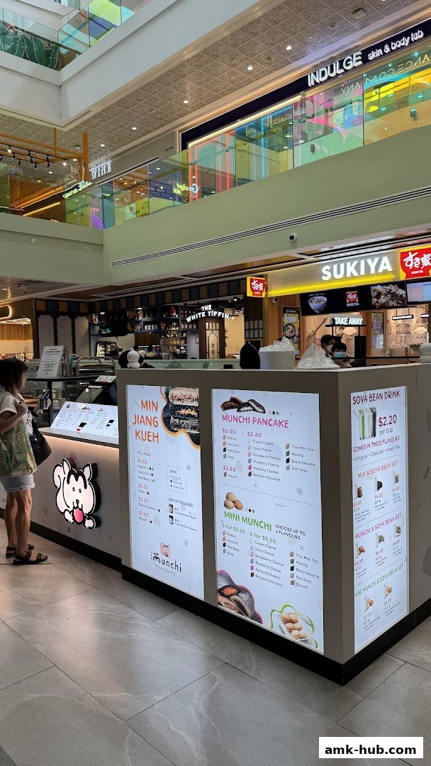 A brightly lit food stall in a mall featuring a menu for Munchi Pancakes and Soya Bean Drinks.
