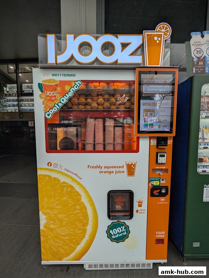 A vending machine offering freshly squeezed orange juice with a large orange graphic.