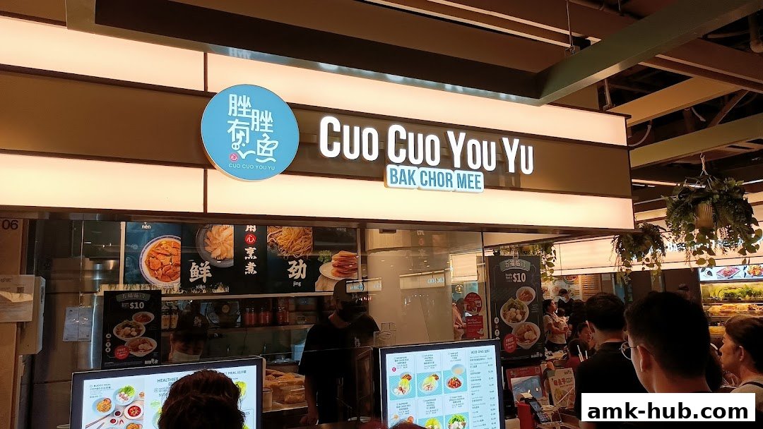 The storefront of Cuo Cuo You Yu, a Bak Chor Mee restaurant, with illuminated signage and food displays.