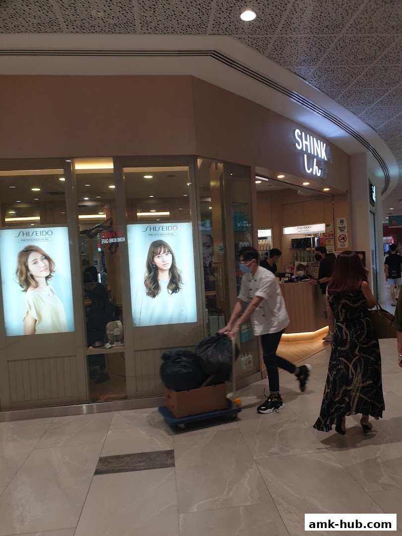 The Shinka shop front with illuminated displays of models and staff inside.