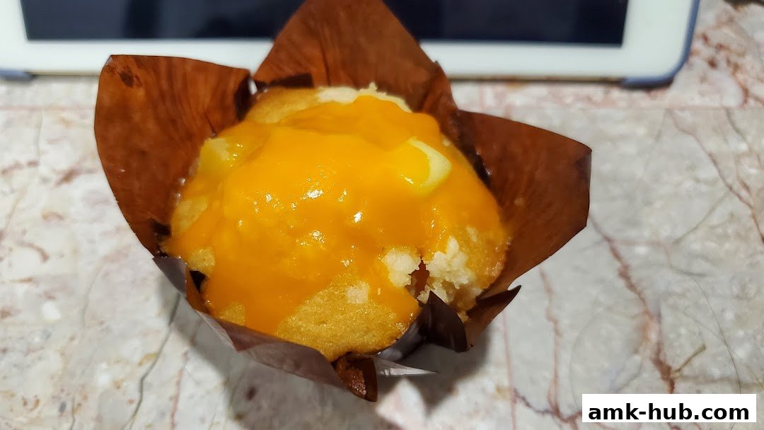 A close-up of a delicious muffin topped with bright orange frosting.