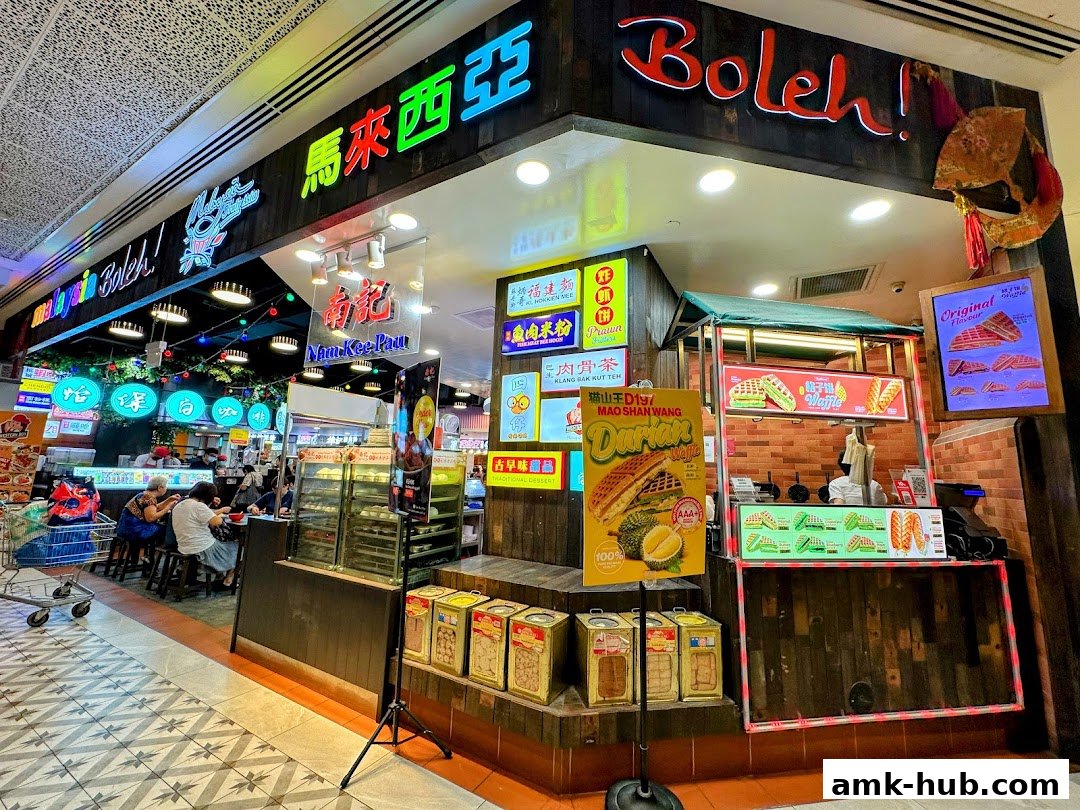 A vibrant Malaysian food stall with colorful signage and various food items displayed.
