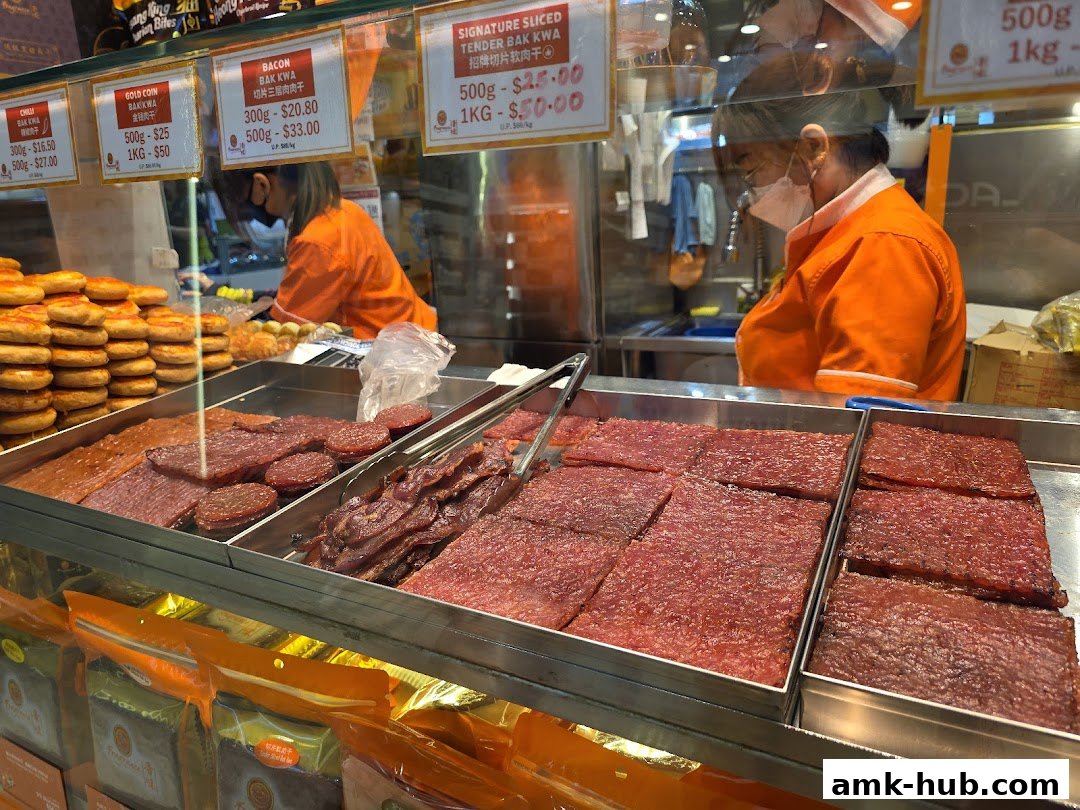 A display of various types of bak kwa with prices and staff preparing orders behind the counter.