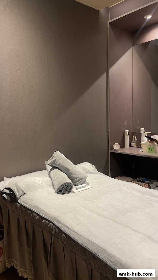 A clean and neatly made massage bed with folded towels and a small pillow.