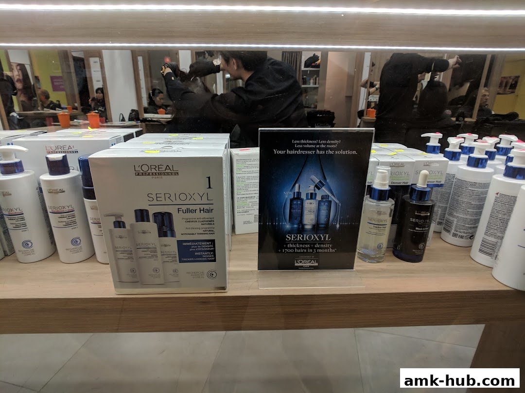 L'Oréal Serioxyl hair products displayed on shelves, with a promotional sign.