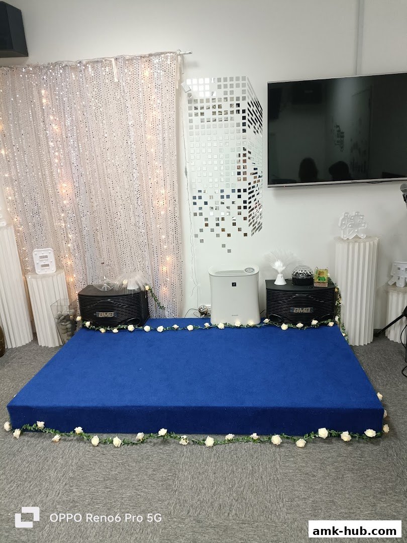 A blue stage with speakers, a TV, and decorative elements, set up for an event.