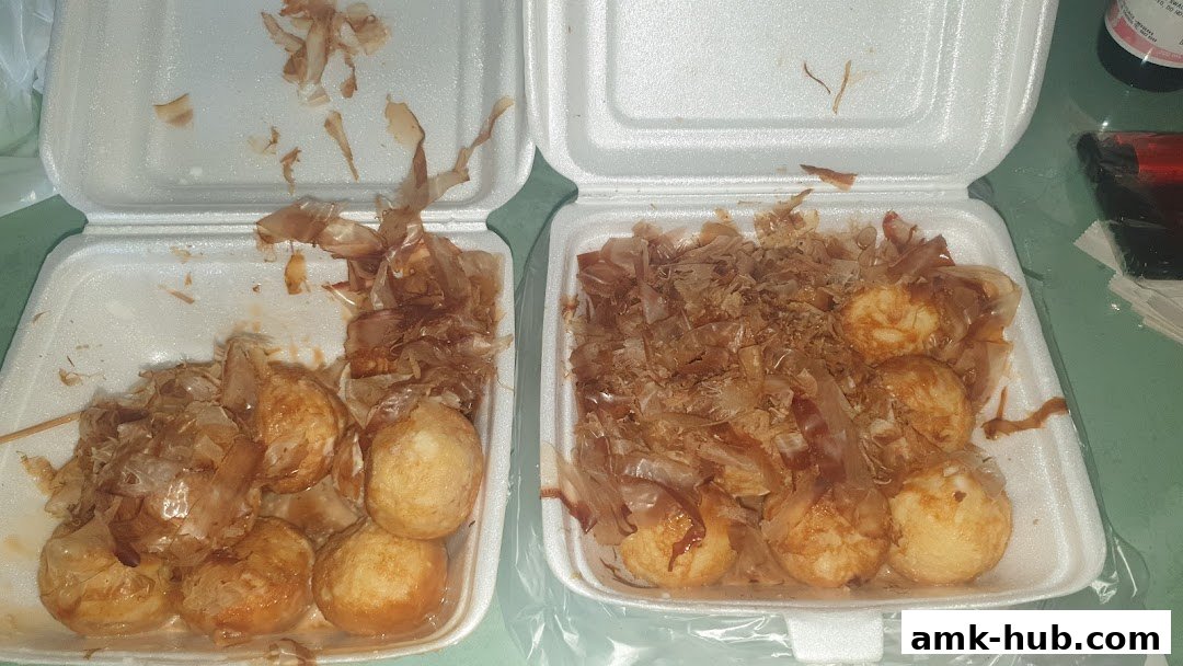 Two open styrofoam containers filled with takoyaki, topped with bonito flakes.