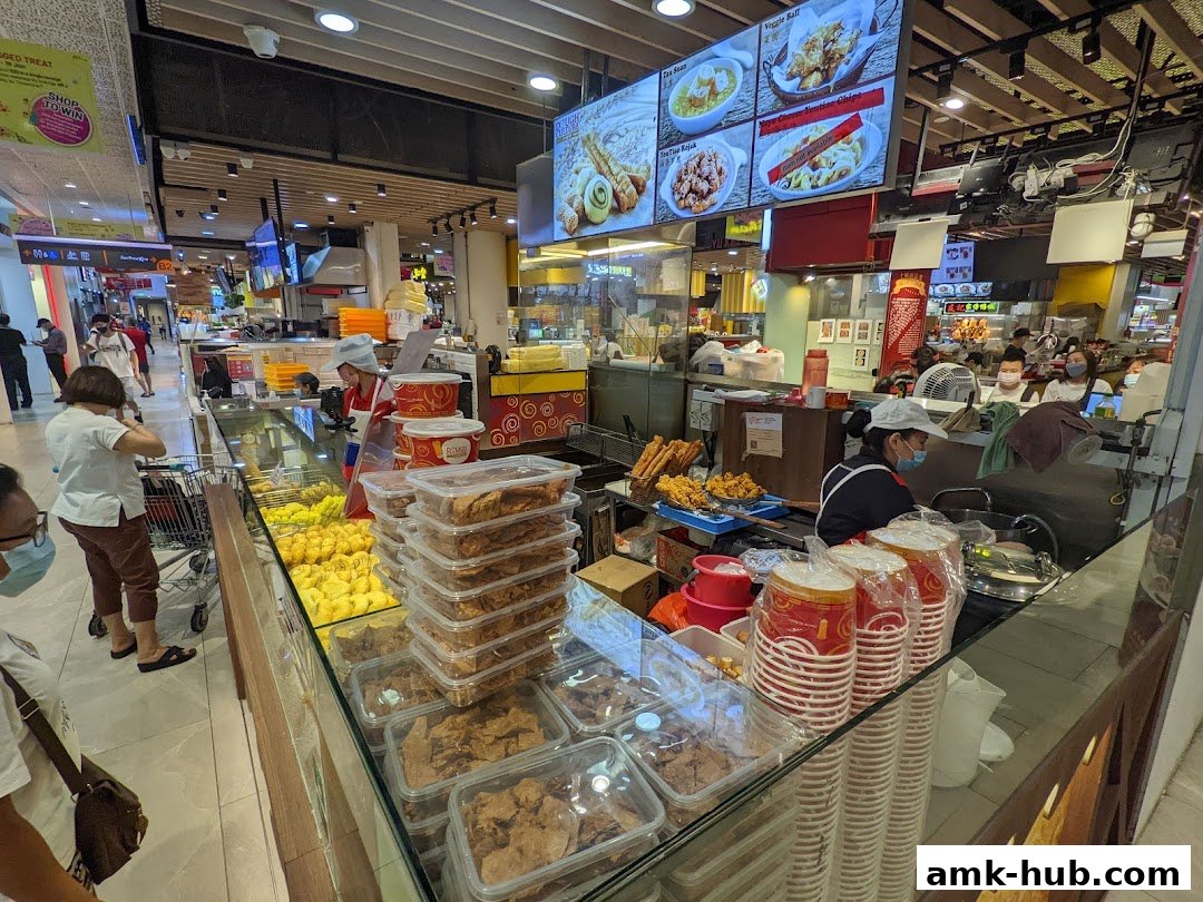 A food stall in a mall with various fried snacks and drinks displayed.