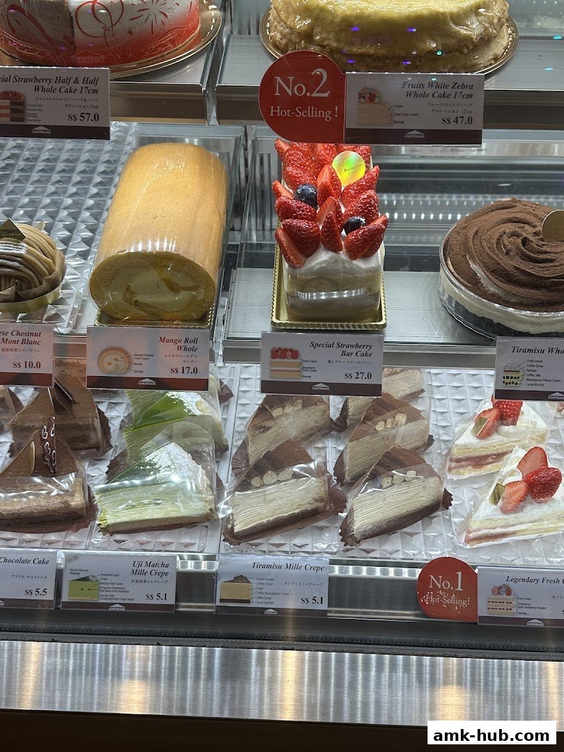A display case filled with various cakes and pastries, including roll cakes, mille crepes, and fruit-topped cakes.
