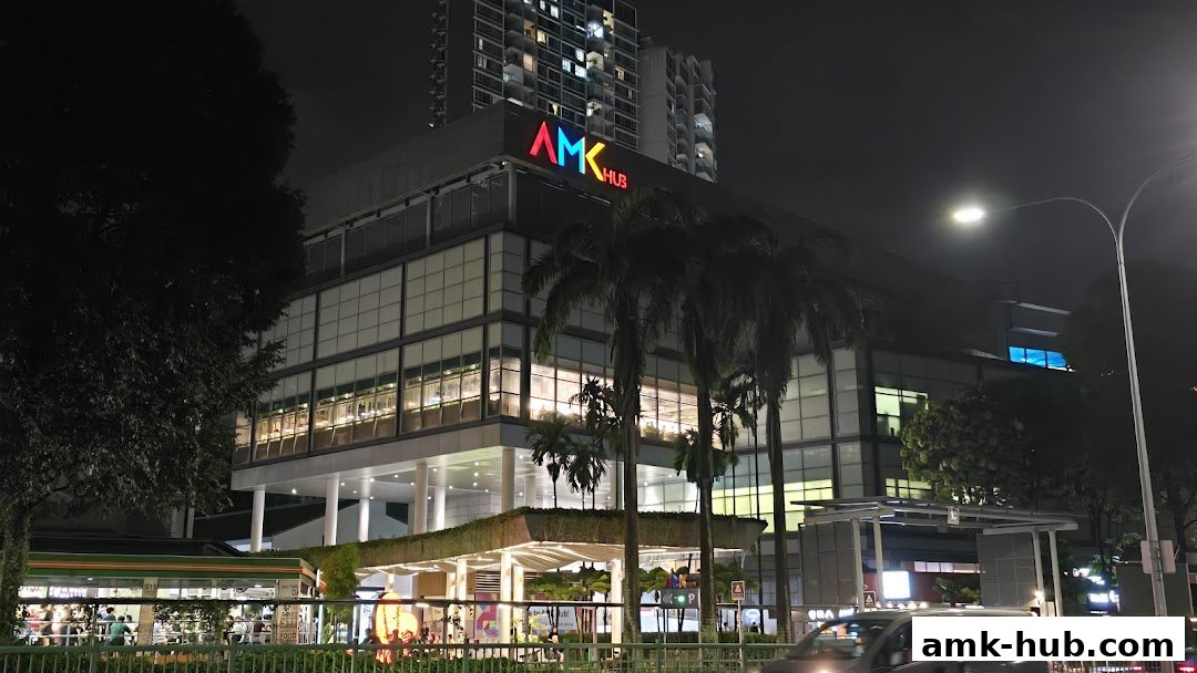 Night view of the AMK Hub shopping mall with colorful signage and illuminated windows.