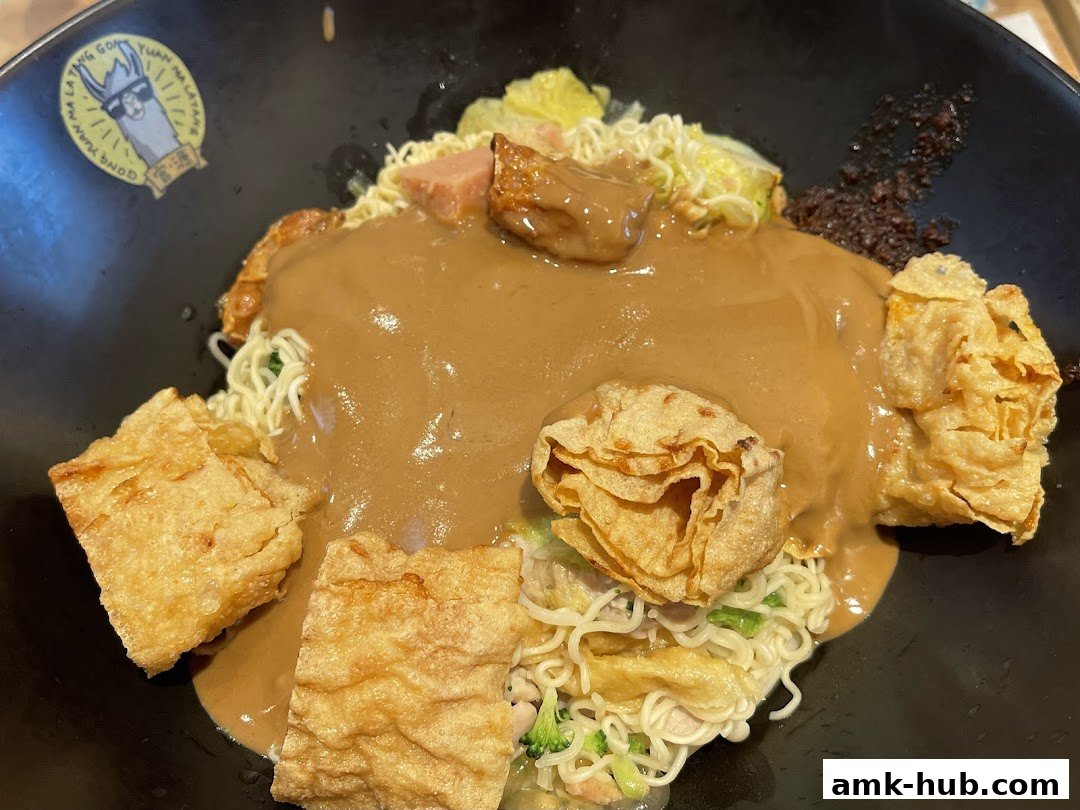 A close-up of a bowl of Mala Tang with noodles, tofu skin, and a rich peanut sauce.