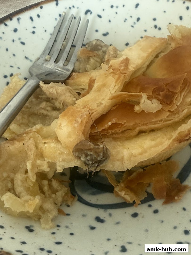 A close-up shot of a flaky pastry with a fork on a speckled plate.