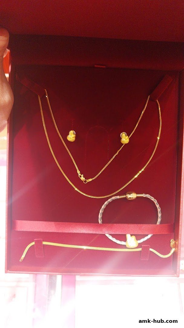 A red jewelry box displaying a gold necklace, earrings, and bracelets.