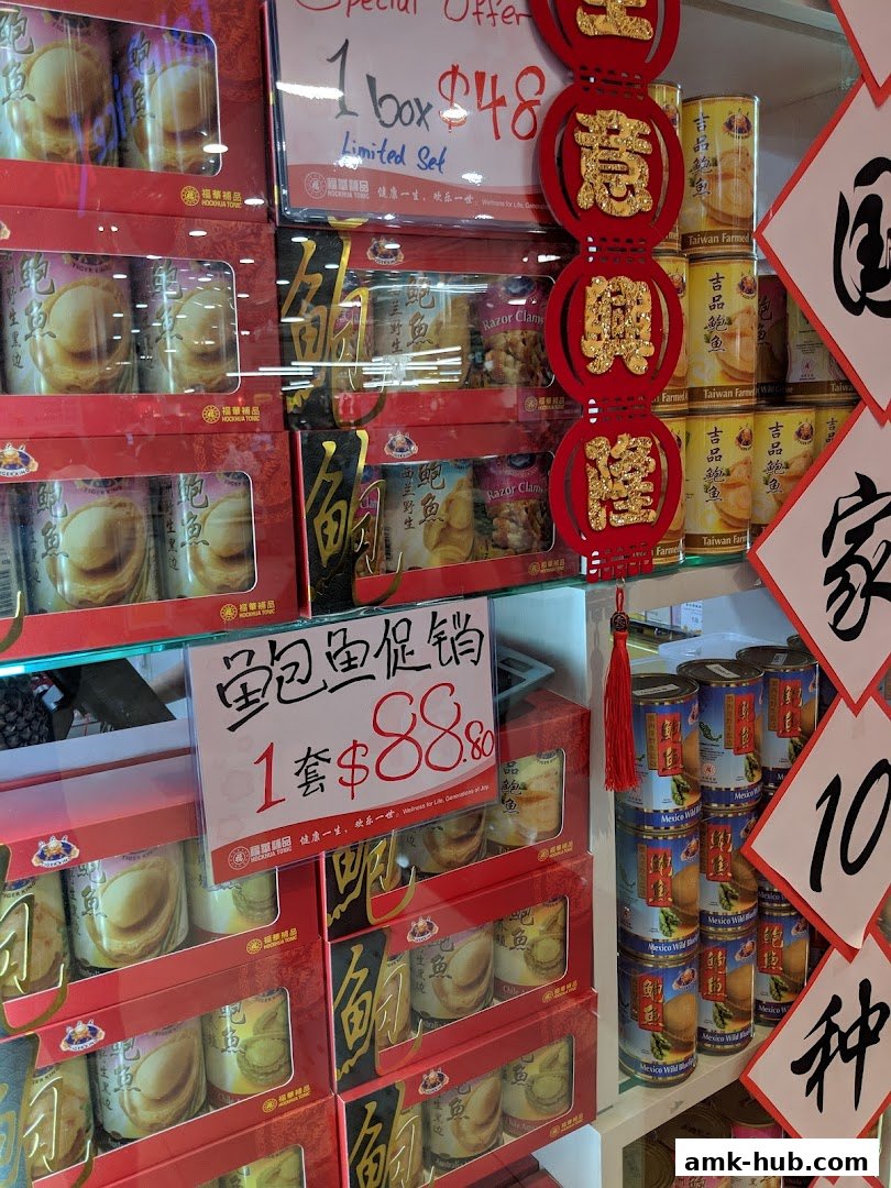 A display of canned abalone and razor clams with special offer signs and Chinese New Year decorations.