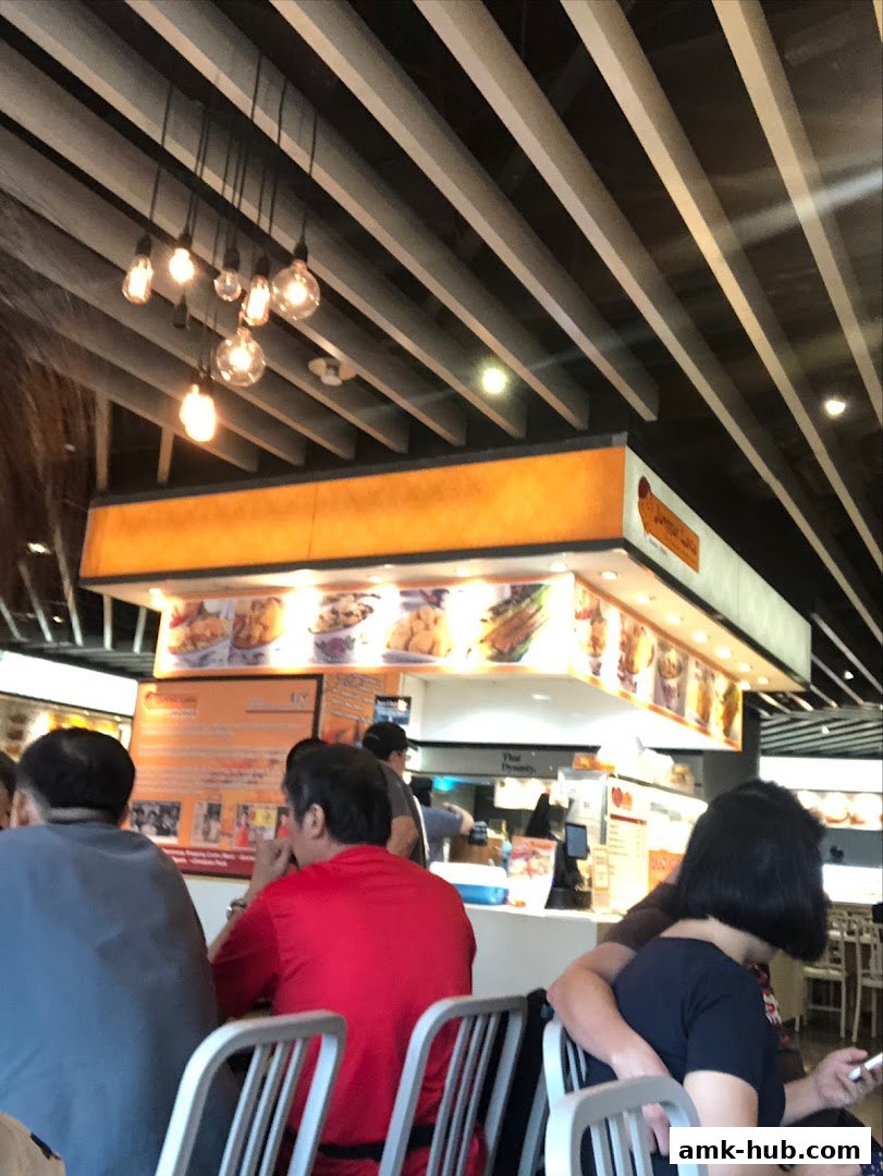 Diners seated at a food stall with a menu and food displays visible.