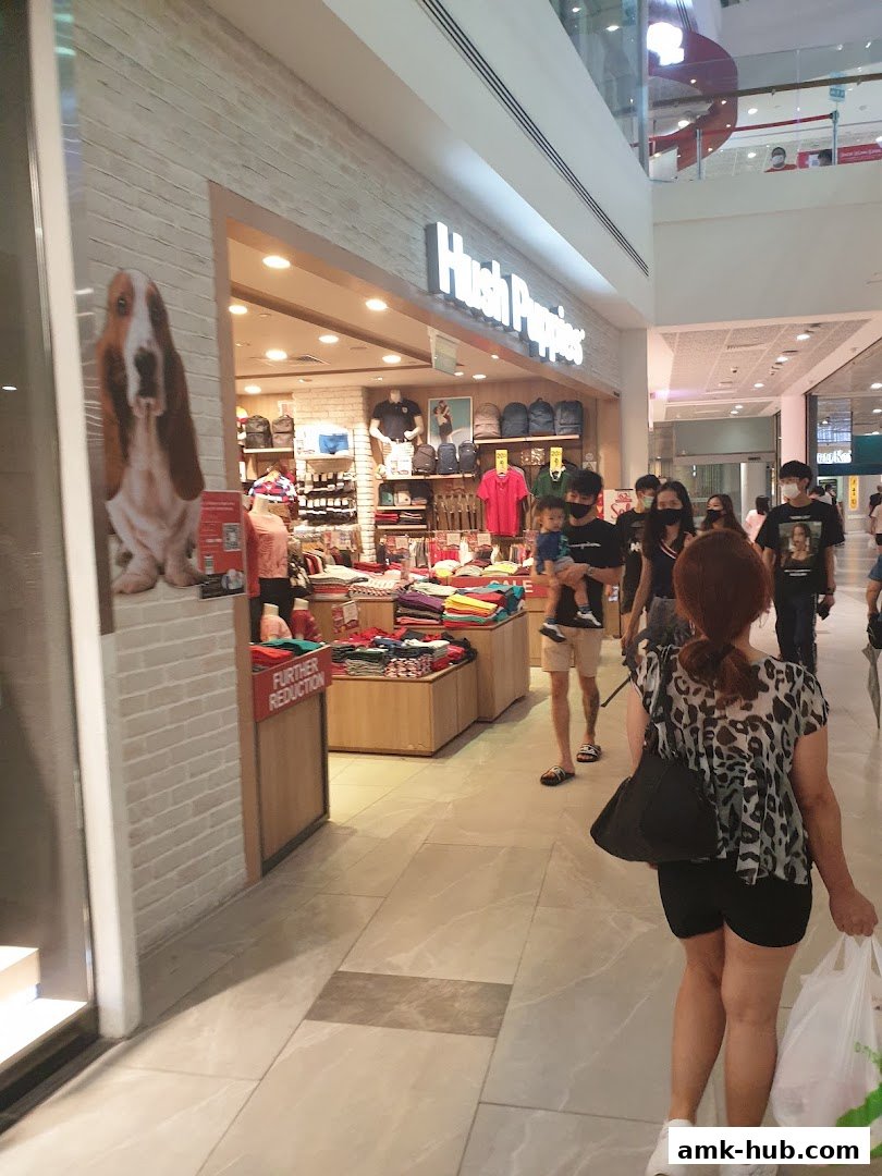 The Hush Puppies store entrance with merchandise displayed and shoppers walking by.
