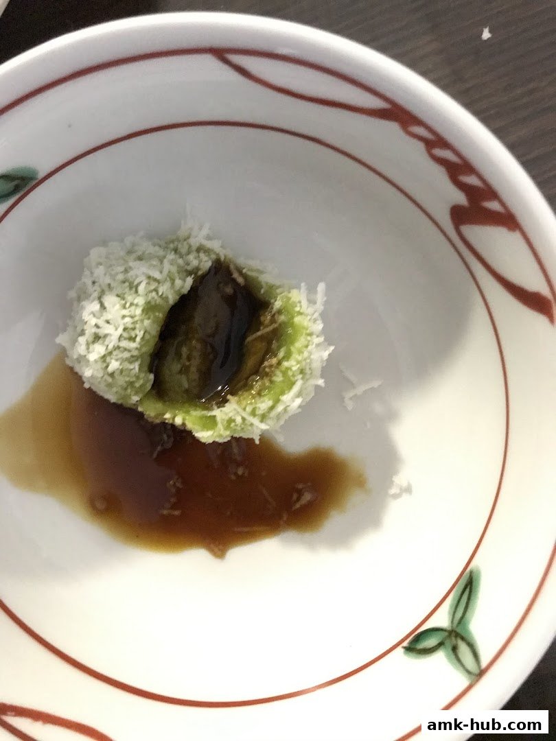A close-up of a traditional Indonesian dessert, Kue Klepon, served in a decorative bowl.