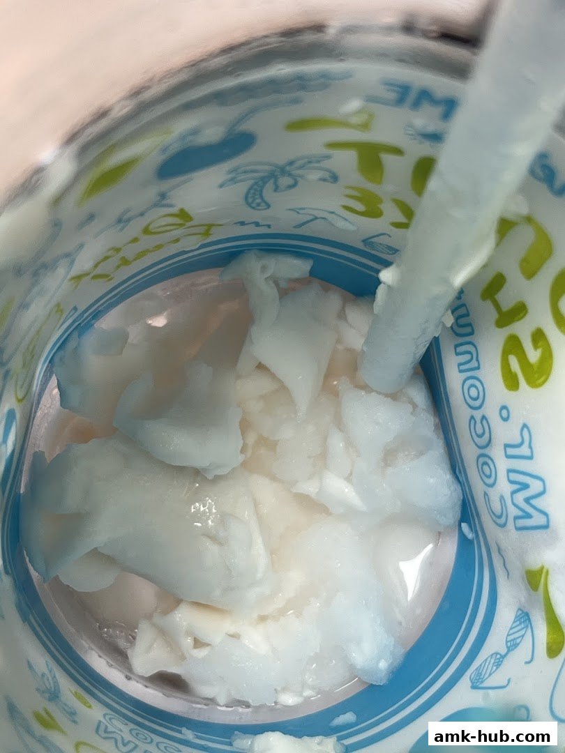 A close-up view of a refreshing coconut drink with chunks of coconut flesh and a straw.
