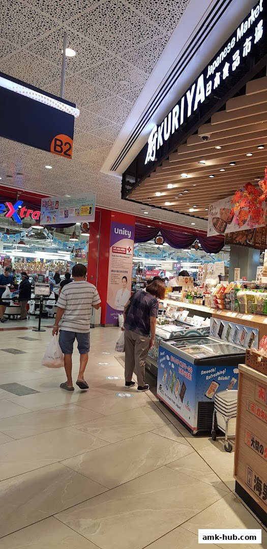 People shopping at Kuriya Japanese Market, with a freezer display and store signage visible.