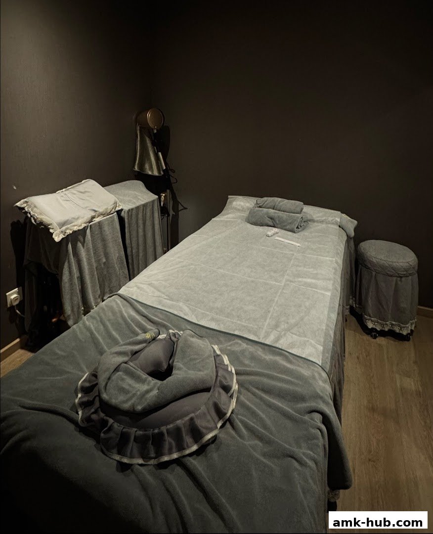 A dimly lit room with two massage beds, one with a face cradle.