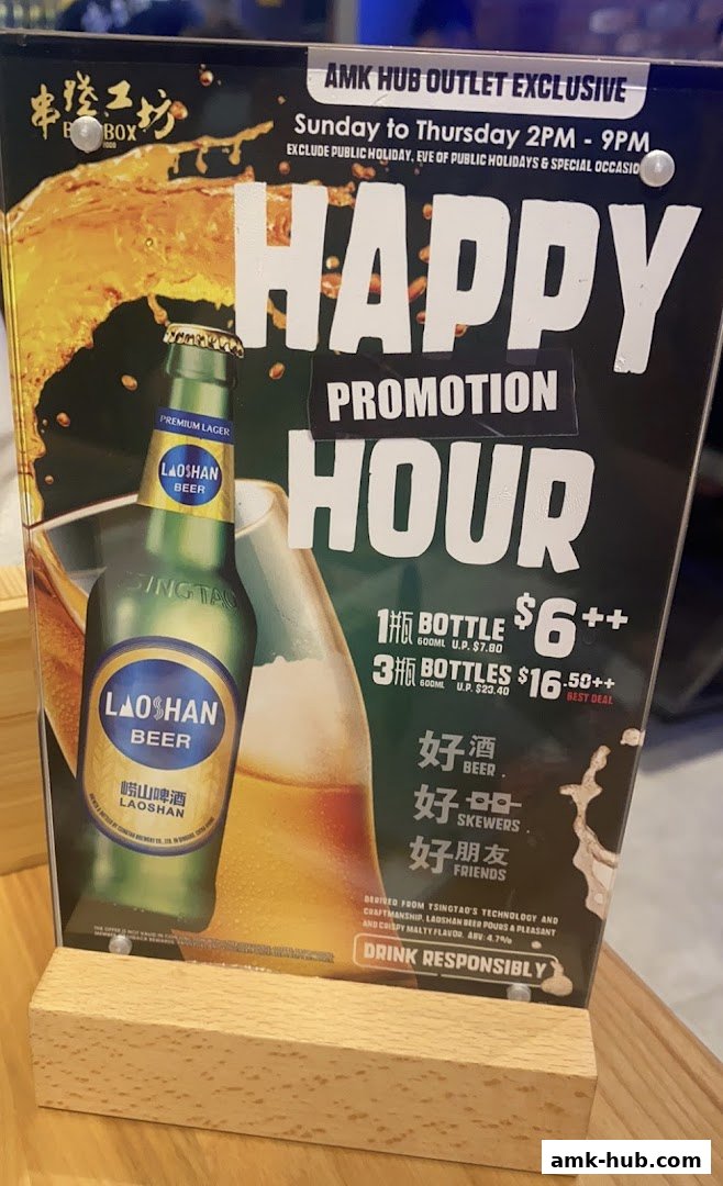 A promotional sign for BBQ Box AMK Hub featuring a happy hour beer promotion.