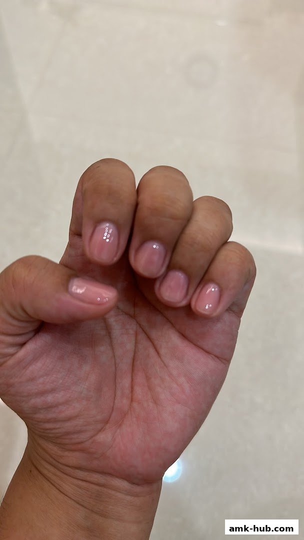 A close-up shot of a hand with neatly manicured nails painted in a subtle pink shade.