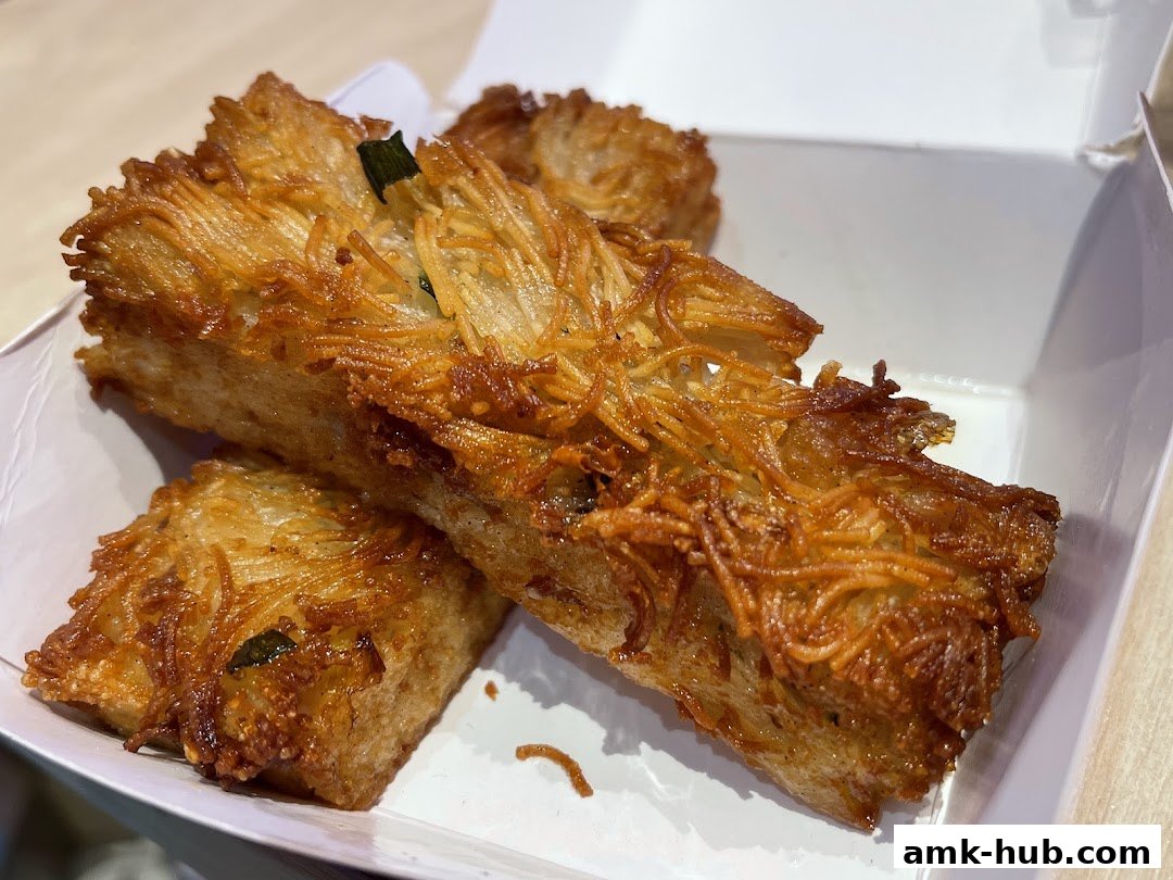 Close-up of crispy fried dim sum items in a white takeout box.