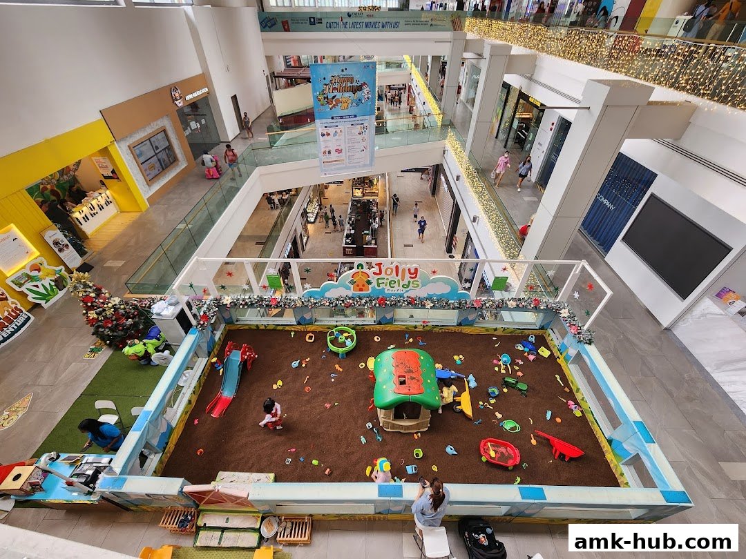 An indoor play area for children with sand, toys, and a slide, set up in a shopping mall.