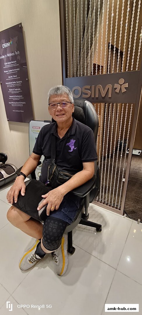 A man sits in a massage chair at an OSIM store, with store branding visible.