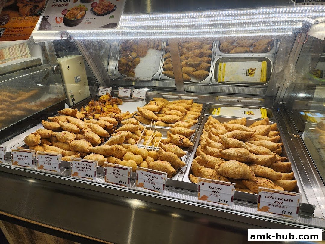 A display case filled with various fried pastries and snacks, labeled with their names and prices.