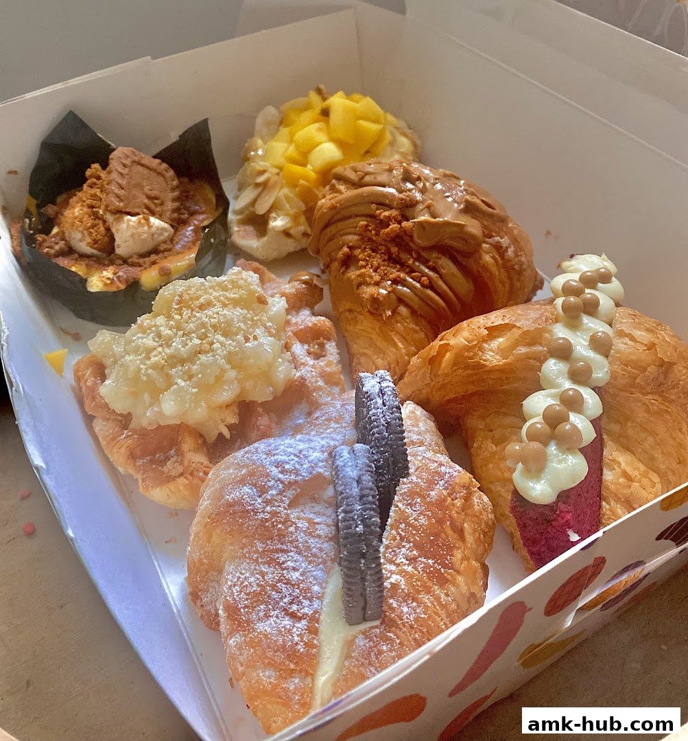 A box filled with assorted croissants and pastries, showcasing various toppings and fillings.