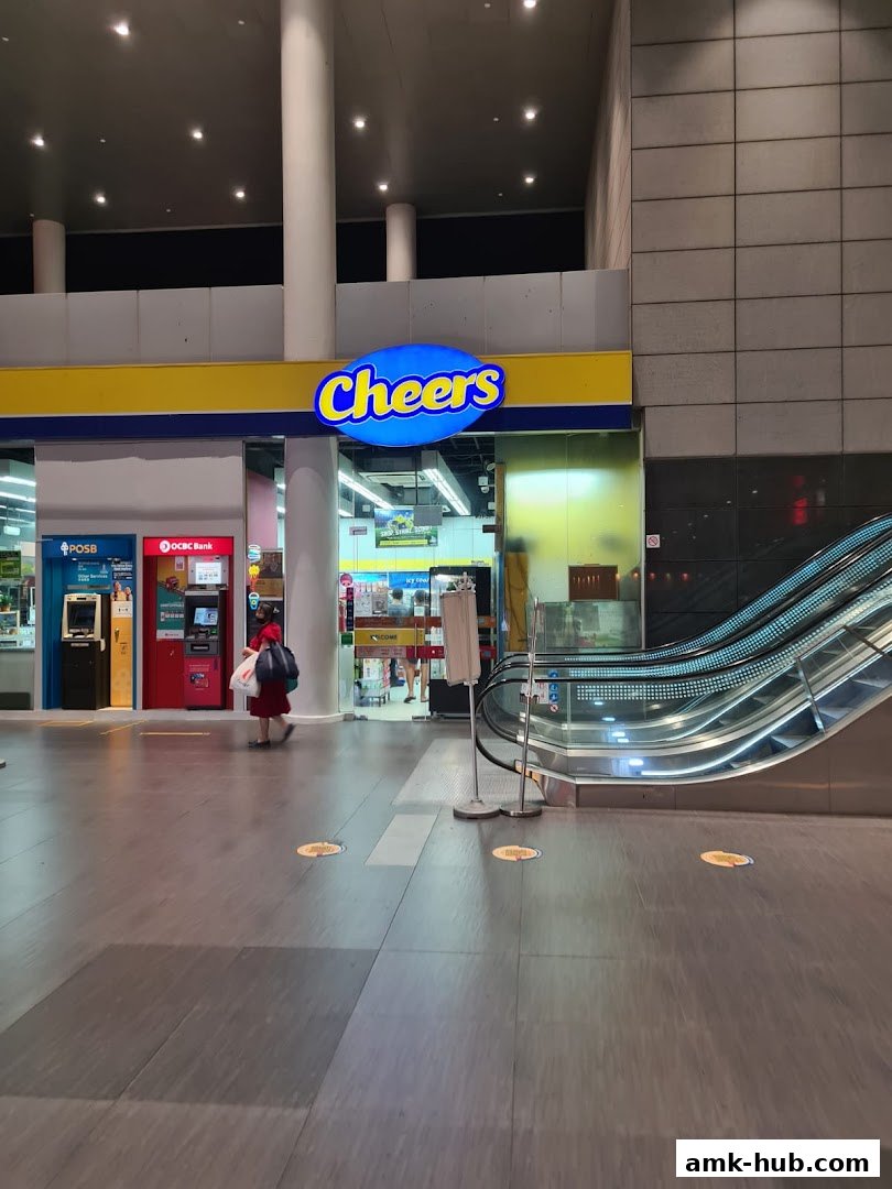 The exterior of a Cheers convenience store with ATMs and an escalator nearby.