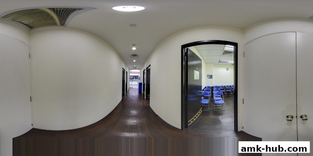 A panoramic view of a clean, modern hallway with several doors and a room with blue chairs.