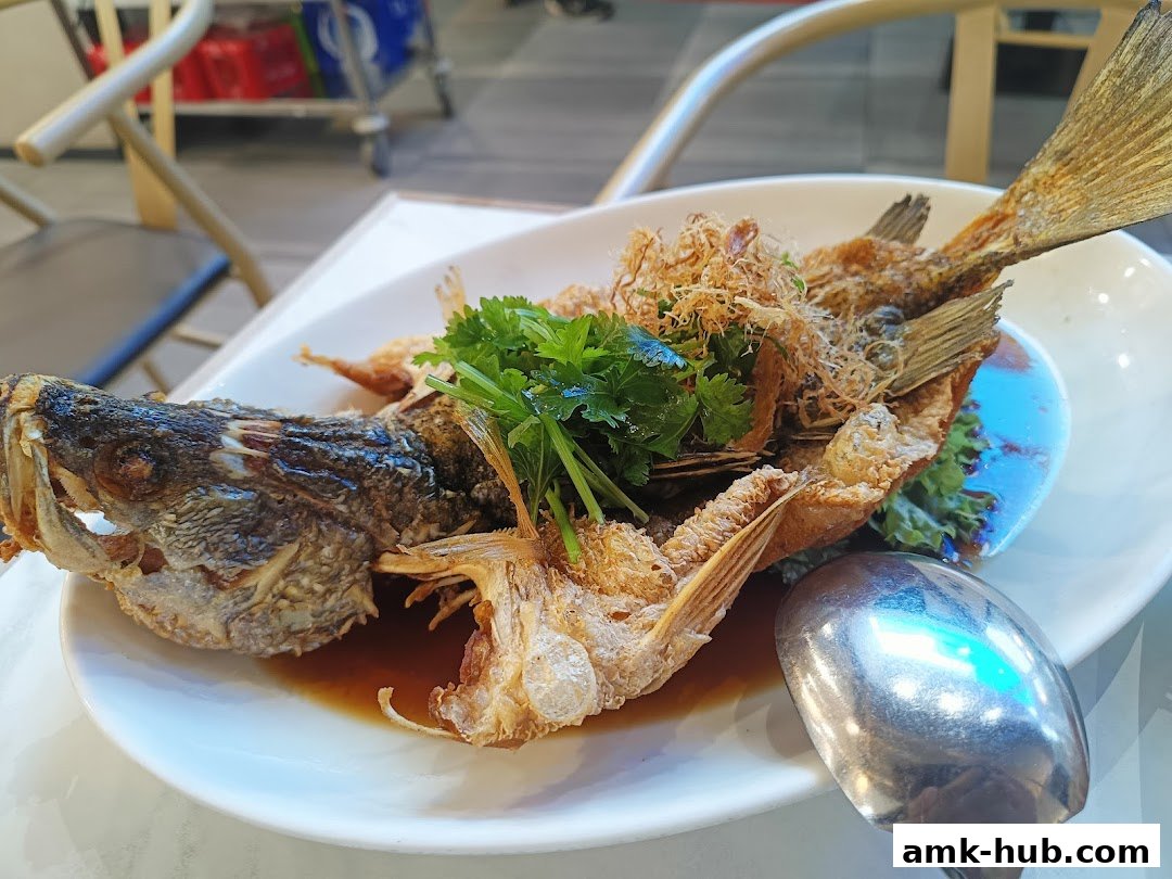 A whole fried fish dish with crispy skin, garnished with herbs and served with sauce.