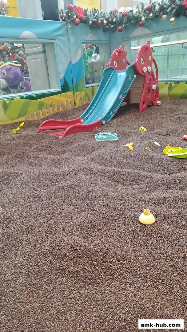 A colorful indoor play area with a slide and sandpit, decorated for Christmas.