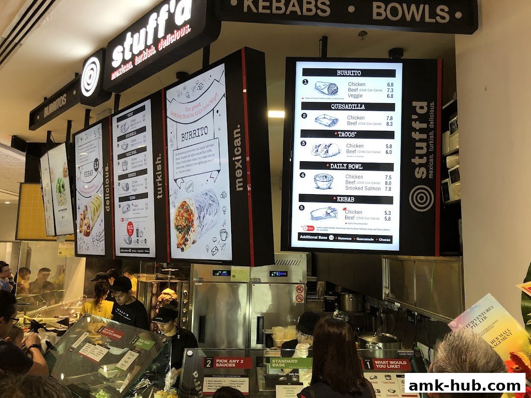 A brightly lit menu board displays various Mexican and Turkish food options at Stuff'd.