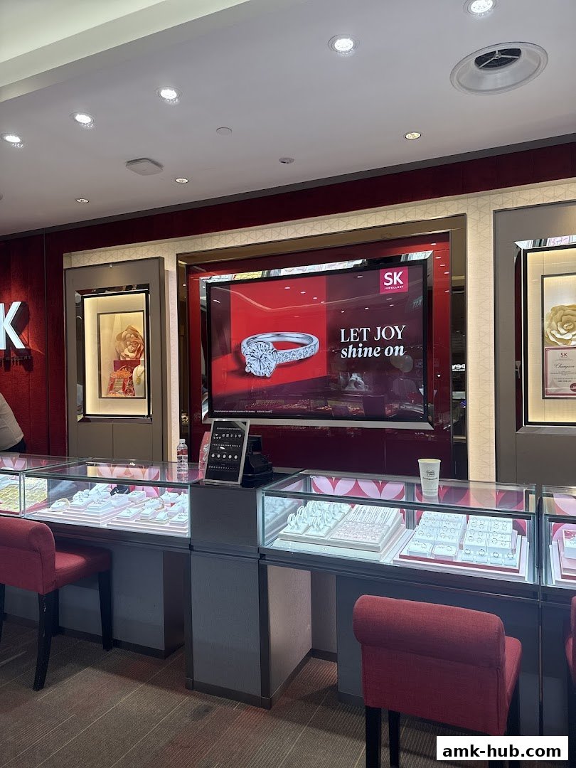 Interior view of SK Jewellery shop with display cases filled with jewelry and a large screen.