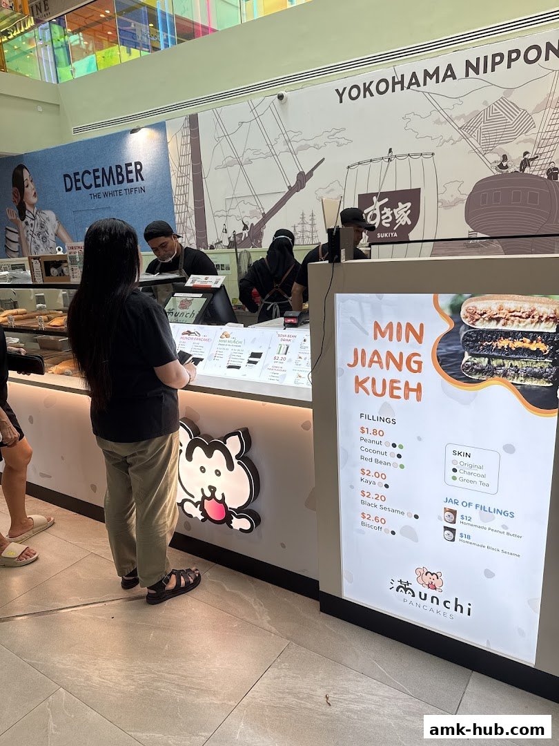 Customers ordering at a counter with a menu displaying Min Jiang Kueh and fillings.