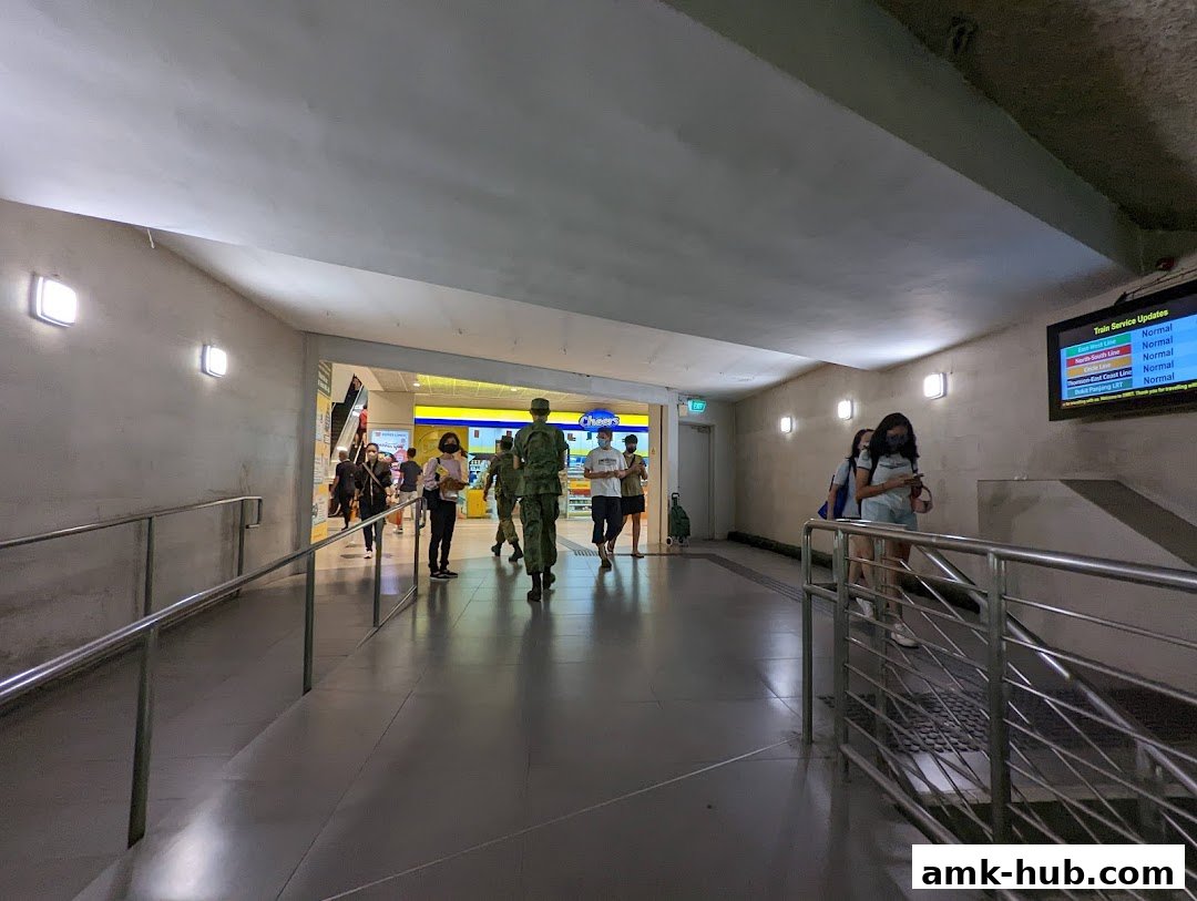 People walking in a well-lit indoor walkway towards a shop entrance.