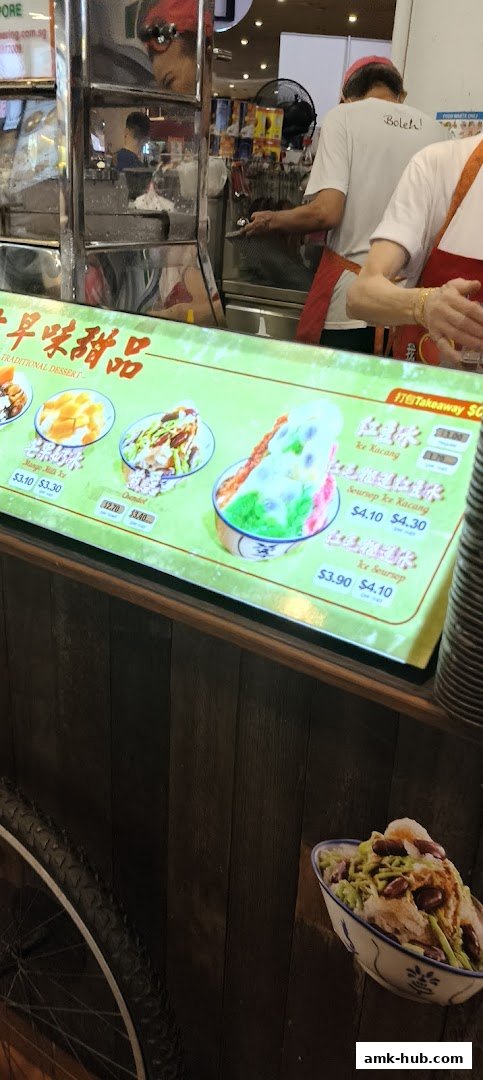 A brightly lit menu board displays various traditional desserts with prices.