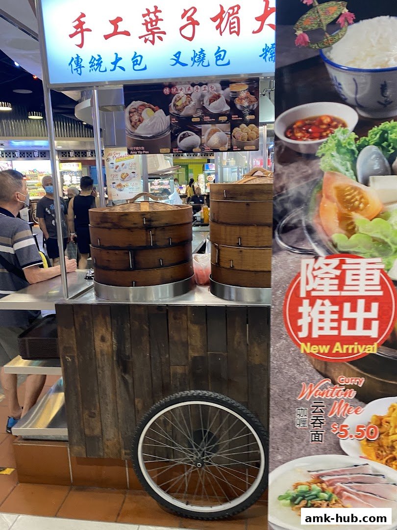A food stall with steaming baskets and a menu featuring traditional buns and noodles.